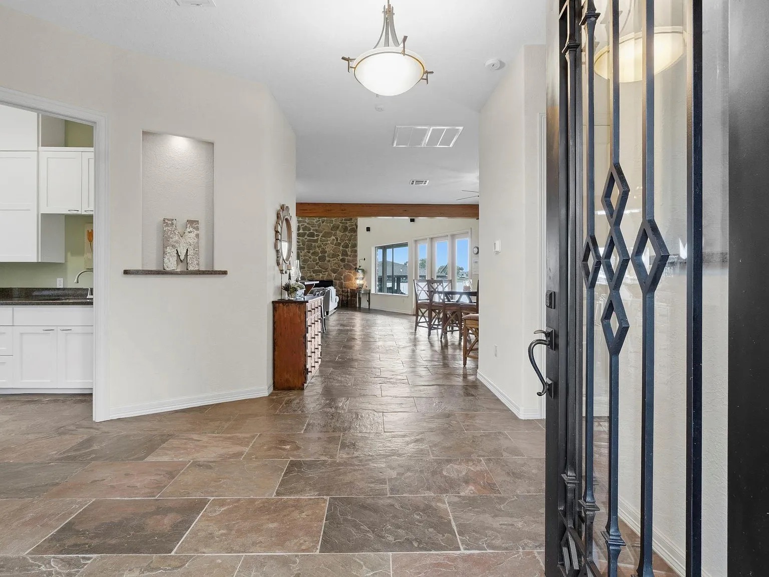 The slate entry hall at 295 Bayview Lane, ceiling lantern overhead and the great room visible through the open archway with Lake Livingston beyond