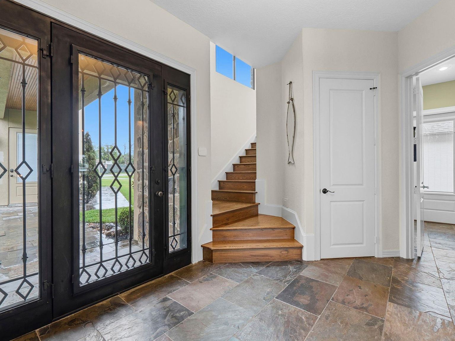 The interior staircase at 295 Bayview Lane with stained wood treads, slate landing, and iron front doors visible at right