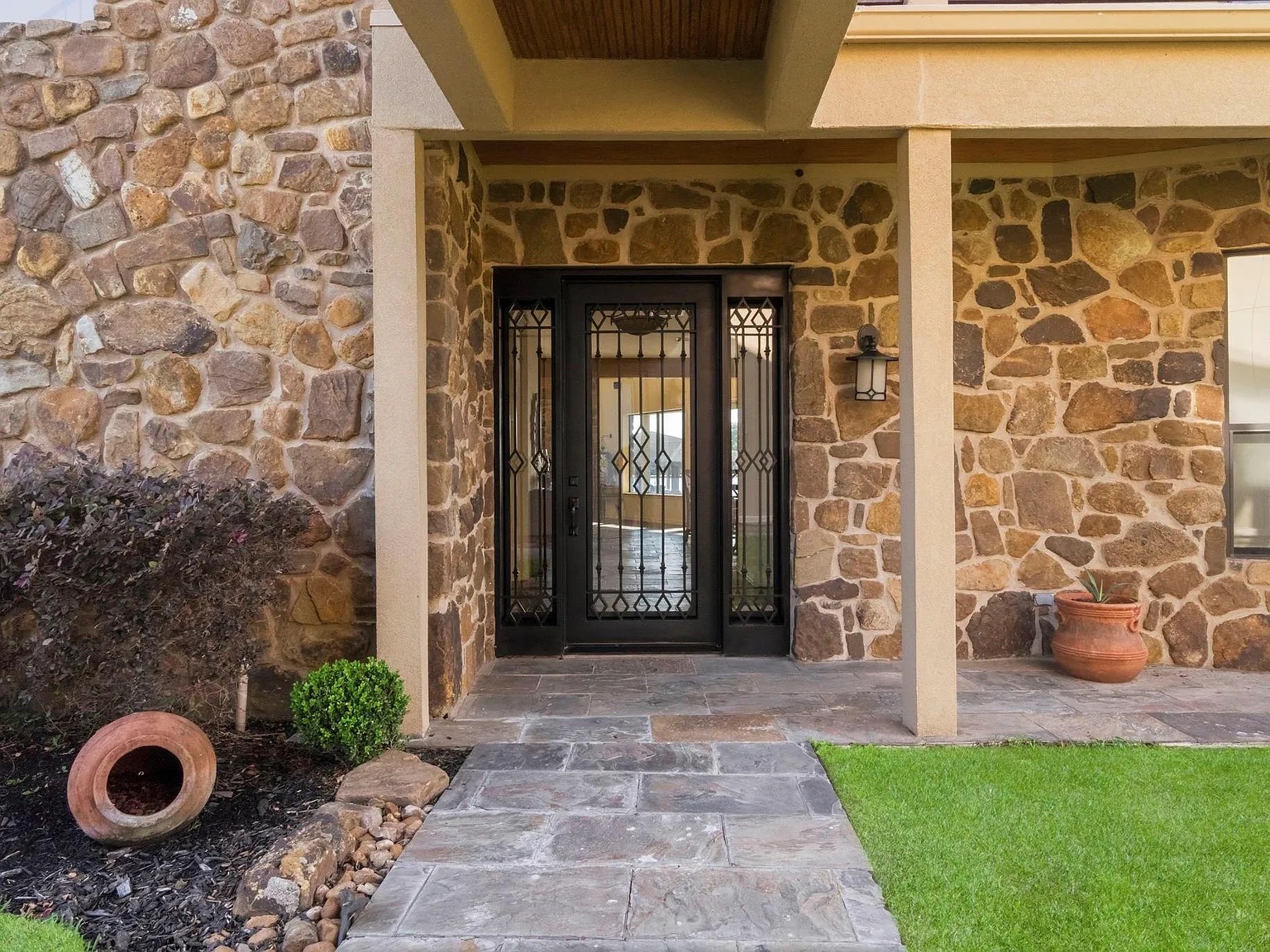 A close view of the stone entry portico and front doors at 295 Bayview Lane, hand-laid stonework framing the iron-and-glass entry
