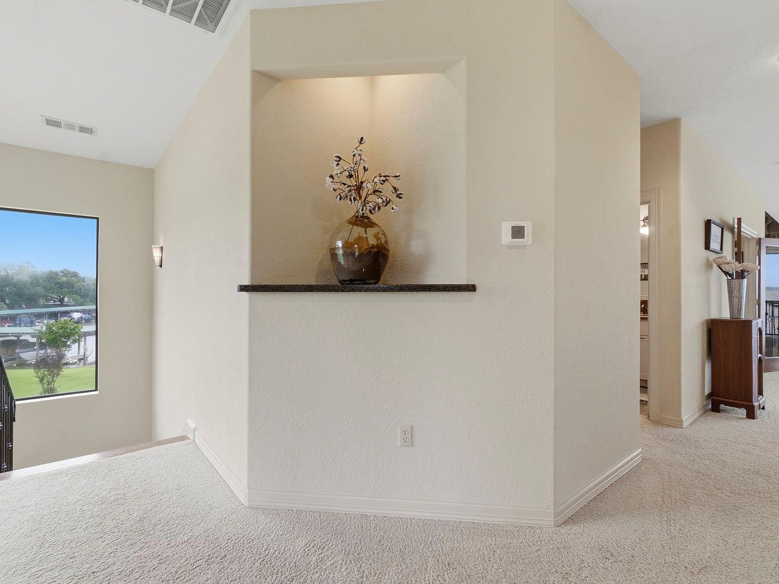 The great room couch arrangement at 295 Bayview Lane facing the two-story stone wood-burning fireplace with paired armchairs and a low concrete coffee table on a woven rug