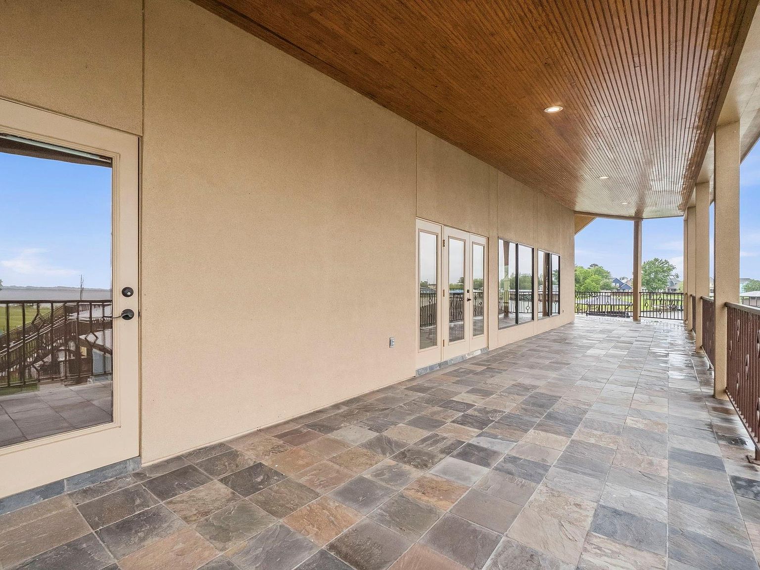 The breakfast and family area at 295 Bayview Lane, light streaming through tall lake-facing windows onto a long wood dining table with iron candelabra above